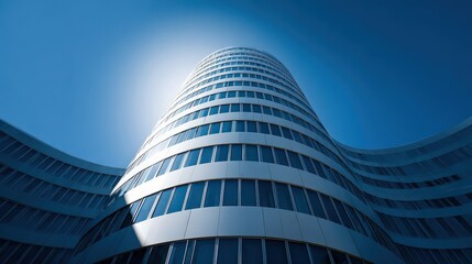 Modern architectural building with a curved glass facade reaching towards a bright blue sky, creating a futuristic and abstract urban landscape.