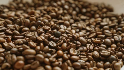 Fotobehang Koffiebonen Closeup of roasted coffee beans showcasing rich brown textures and aromatic quality in a background suggesting freshly brewed beverages  © Krakenimages.com