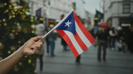 Hand holding puerto rican flag outdoors in a crowded city street with blurred background. © Krakenimages.com