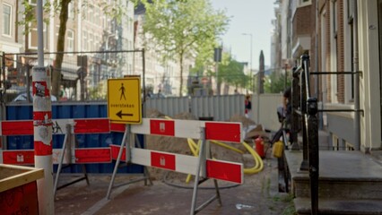 Blurry view of a defocused construction site with bokeh effect showcasing traffic barriers and warning signs against an urban backdrop under clear daylight.