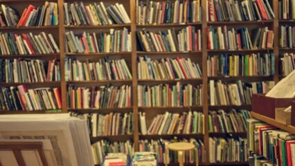 Blurred view of a library interior with shelves filled with colorful books creating a defocused background and a quiet, academic atmosphere.