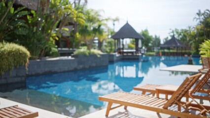 Blurred view of a luxury tropical resort poolside with defocused bokeh capturing serenity and relaxation in an outdoor hotel setting.