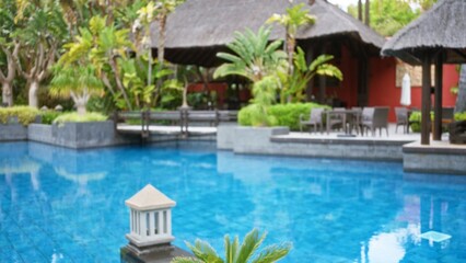 Defocused tropical resort pool setting with lush greenery and luxury villas, showcasing a serene and inviting atmosphere perfect for relaxation.