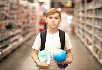 Cute teenager kid boy choosing school stationery in supermarket