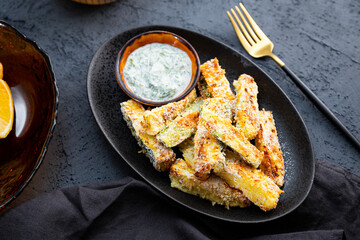 Healthy zucchini fries with yogurt and herbs sauce on the table