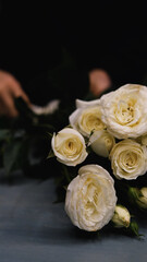 Beautiful white roses in a flower shop. Florist assembles a bouquet to order