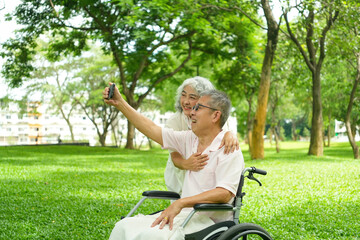 Fototapeta premium Happy Asian Senior Couple Relaxing Together in Park with Wheelchair