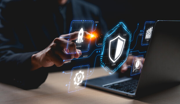 A person interacts with digital security icons on a laptop, highlighting cybersecurity and technology themes in a modern workspace.