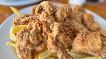 Crispy Fried Chicken Strips with French Fries Served on a White Plate Over Rustic Wooden Table