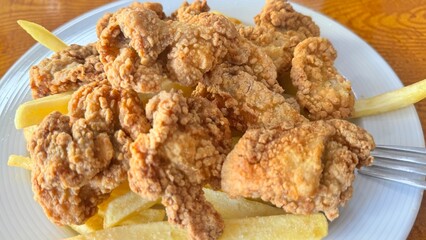 Crispy Fried Chicken Strips with French Fries Served on a White Plate Over Rustic Wooden Table
