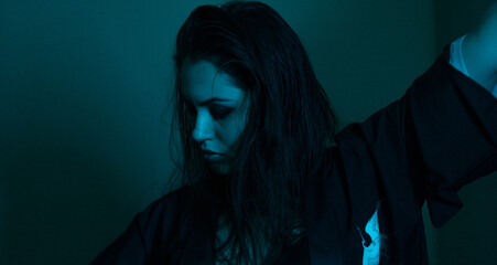 Moody portrait of a woman in colorful lighting, emotional expression in red, blue, and teal tones.