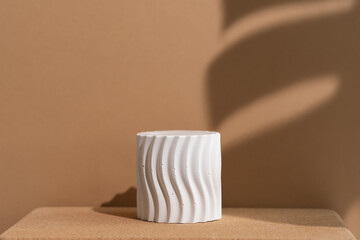 White podium with the shadow of a monstera leaf on a wooden beige background. Geometric premium scene for advertising and presentation your product. Showcase, display case