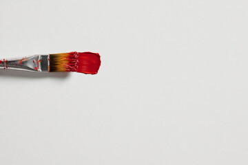 a paintbrush with a red handle on a white surface