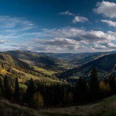 Obraz premium Panoramic View of Vibrant Autumn Valley with Rolling Hills and Dramatic Cloudy Sky at Dusk