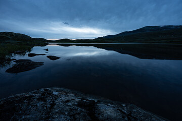 Summer night in Norway, with the bright night sky and the silhouette of gently sloping rocky mountains reflected in a highland lake, Ål, summer in Norway