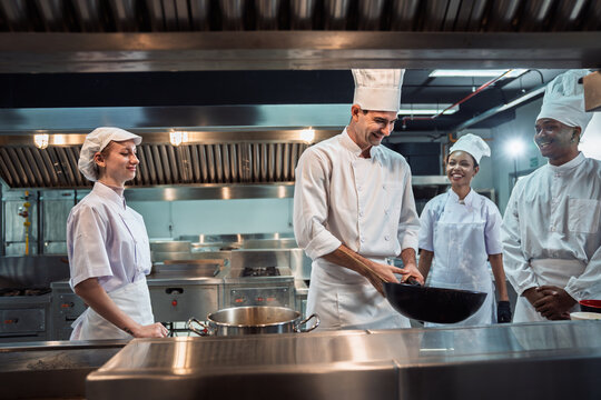 Cooking Class in Commercial Kitchen , Diverse Culinary Student Receives Hands-On Training from Head Chef, Learning with Passion and Focus