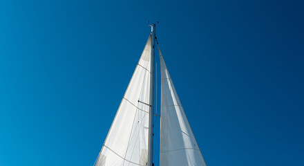 White Sailboat Sail Against Bright Blue Sky.