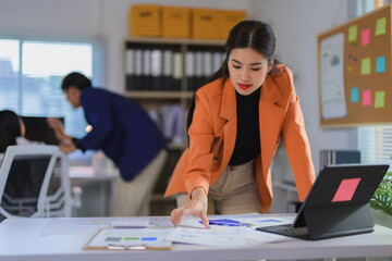 Asian businesswoman analyzing financial charts and graphs at office desk