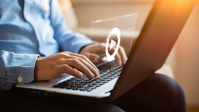 Person typing on laptop with holographic play button hands blue shirt