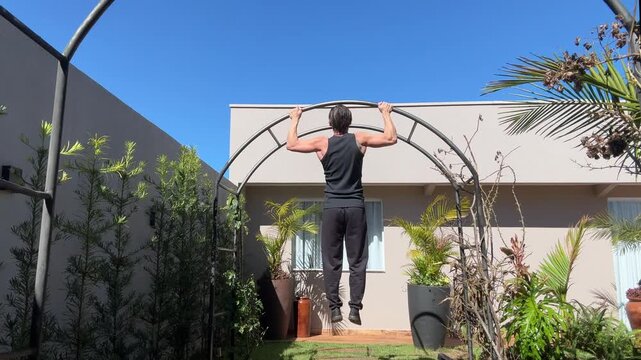 homem treinando barras em jardim de casa