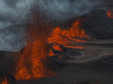 Aerial view of fiery lava erupting and flowing dramatically against the dark volcanic landscape, creating a stark contrast of heat and ash, Grindavik, Southern Peninsula Region, Iceland.