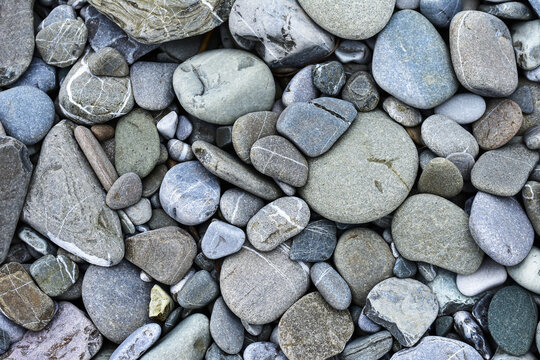 Background with round pebble stones. Stone beach smooth. Top view. A lot of sea round pebbles. Natural abstract background. Stone texture.