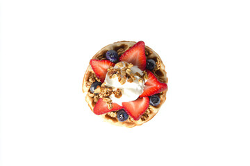 a waffle with strawberries blueberries and granola