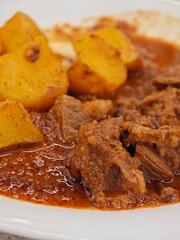 Delicious beef stew served with roasted potatoes in a rustic dining setting