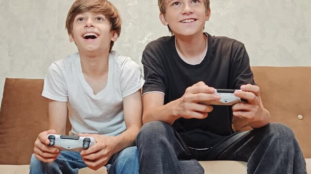 Young Gamer: Teen Boys Immersed in Console Gaming, Boys playing games, Cinematic Shot of Sofa Gameplay with Joystick Close-Up. loving family, two brothers playing together.