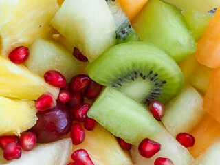 A bowl of fruit with a kiwi in the middle