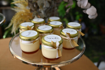 close up of a glass pots, personalized dessert pots, personalized dessert jars for christening, creamy pudding favors with ribbon, elegant baptism party sweets

