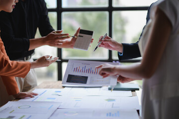 Business team analyzing financial data and company performance using charts and calculator