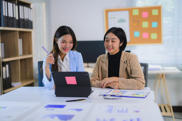 Asian businesswomen working together using tablet and analyzing financial charts at the office