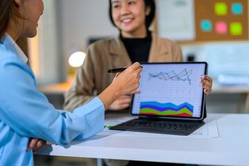 Businesswomen analyzing financial charts and graphs on digital tablet during a meeting