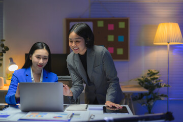 Asian businesswomen working late using laptop in modern office