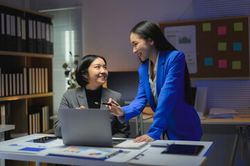 Asian businesswomen discussing and working late together using laptop in office