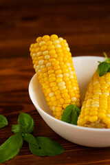 fresh corn on a wooden background with greenery