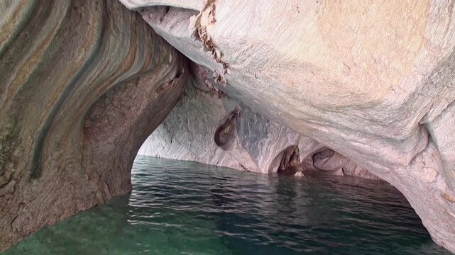 Gentle waves lap against the rocks as sunlight filters into a partially submerged cave in The Baths National Park on Virgin Gorda. A stunning natural archway is visible.