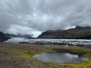 Moss-covered land with lake and glacier backdrop.