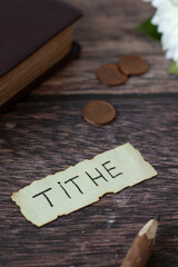 Tithe, handwritten text with coin money and holy bible on wooden background. Christian biblical concept.