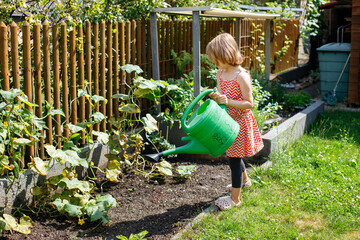 little girl watering plants in a garden in germany