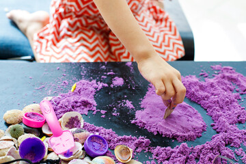 child playing with purple sand