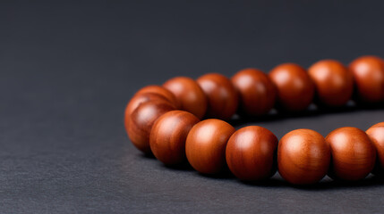 Close-up of a polished wooden bead bracelet arranged on a dark surface, highlighting texture and warm tones.