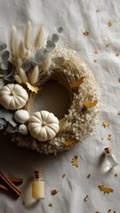 Autumn wreath with white pumpkins and gold paper bats on linen surface