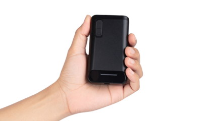 Hand holding solar-powered portable charger with LED indicator, isolated on a transparent background