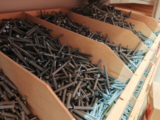 different types of screws stored in organized bins in a hardware store aisle. Screws organized storage.