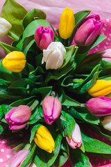 Spring bouquet of colorful tulips wrapped in pink paper with white polka dots. Bunch of many colorful fragrant flowers. Floristry and floral design concept. Floral texture
