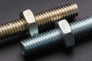 Two bolts with nuts on a dark background