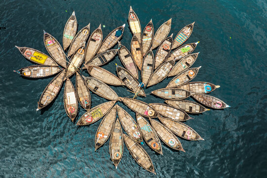 Aerial view of traditional boats clustered together on the shimmering water, their varied colors contrasting with the deep blue, Dhaka, Dhaka District, Bangladesh.