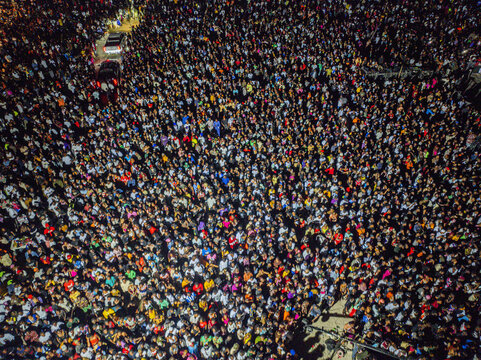 Aerial view of a massive crowd gathered, a sea of faces illuminated under the night sky, creating a vibrant spectacle, Okrika, Alesa, Nigeria.